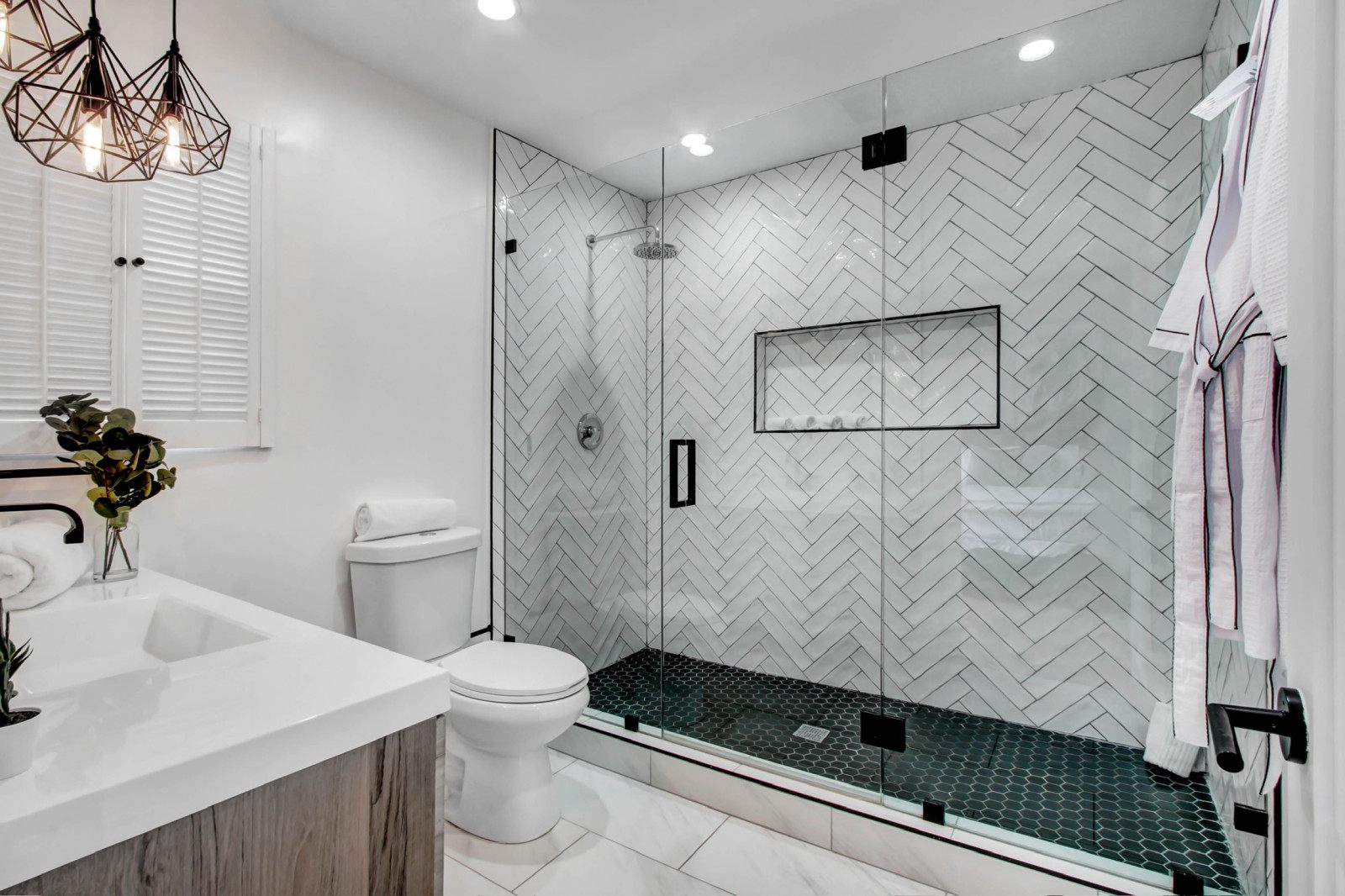 Walk-in shower remodel with herringbone tile and frameless glass