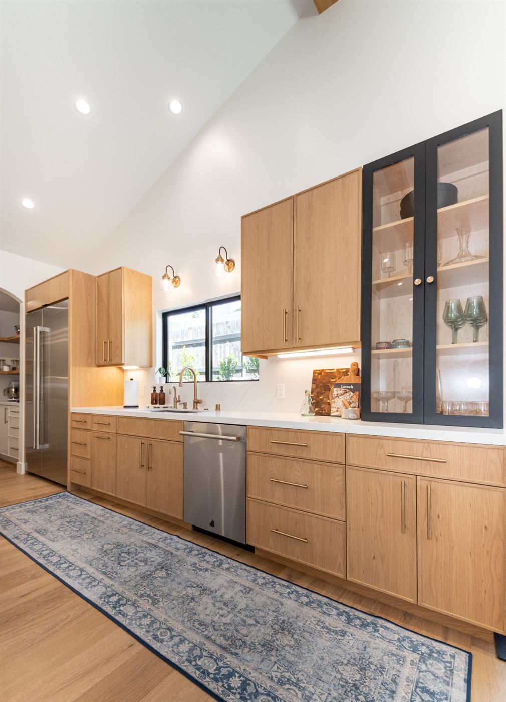 Kitchen with white countertop, light wood cabinets and brass handles