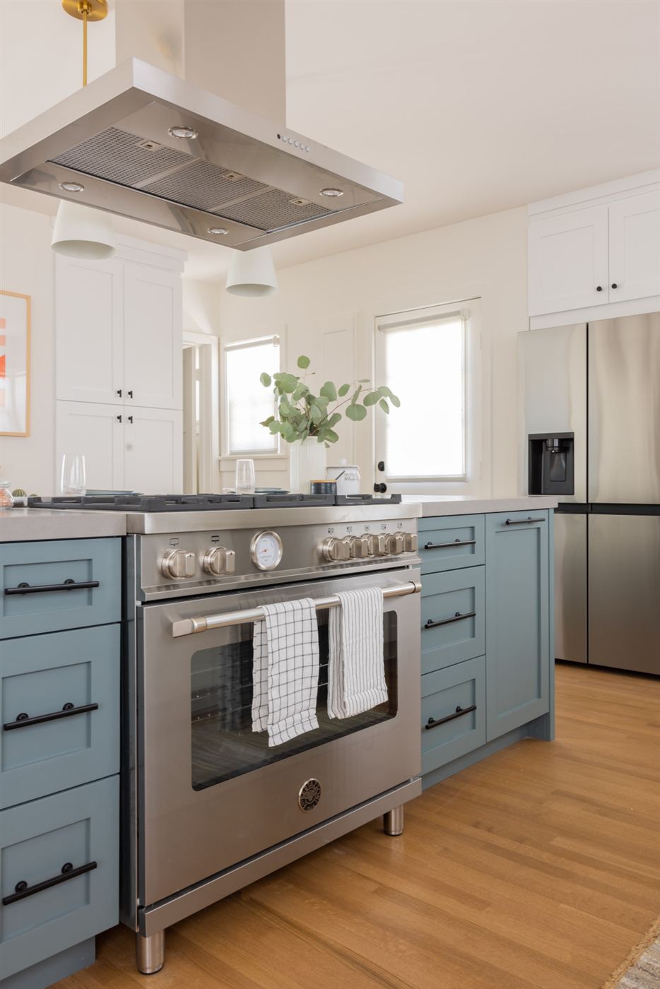 Modern kitchen with muted blue-gray cabinets, black hardware and six-burner range